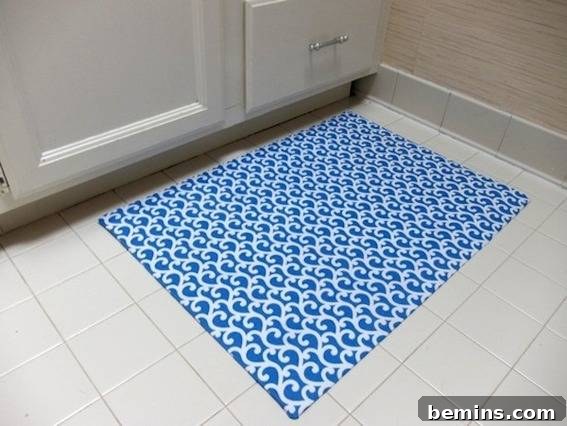 White swirls decorate a rug in front of white cabinets, showcasing a fabric and vinyl flooring bath mat.