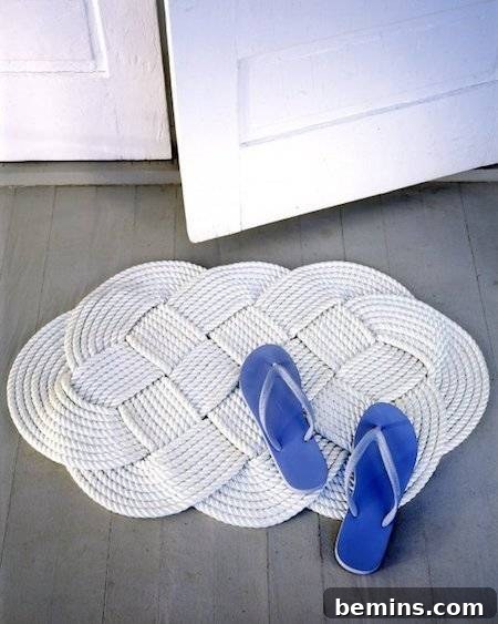 A blue pair of flip-flops it's on a white swirling rug made of rope, showcasing a braided rope bath mat.