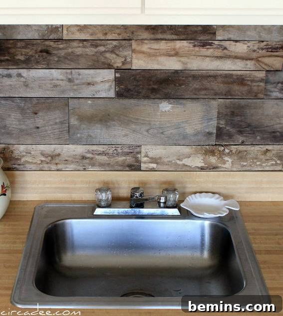 A clean sliver sink has a small white fish plate sitting by the faucet with a faux wood backslash.