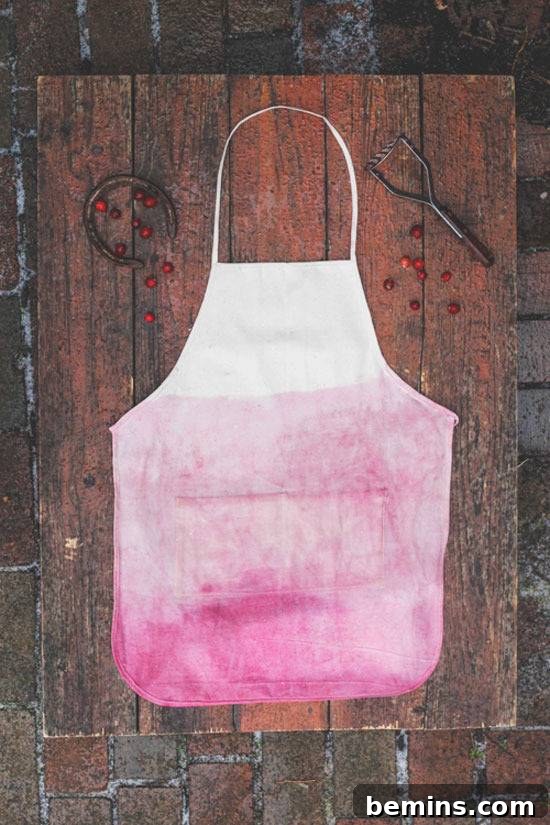 Culinary Creations: 16 Fabric DIY Projects for Home Chefs 12 An apron dyed in a beautiful reddish-pink hue using cranberries, displayed on a rustic wood table.