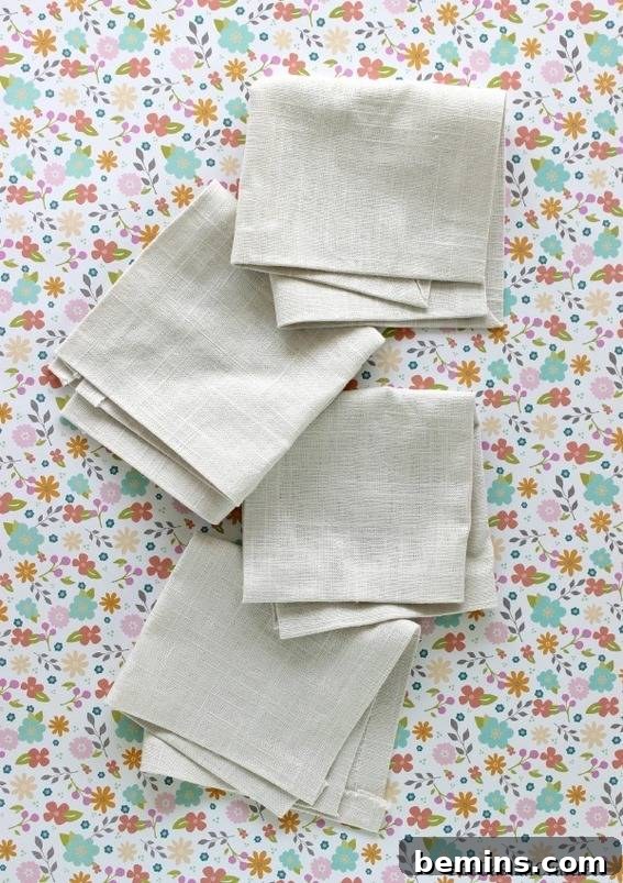 Culinary Creations: 16 Fabric DIY Projects for Home Chefs 13 Four elegantly folded linen napkins on a brown, pink, and green flowered background, showcasing a no-sew project.