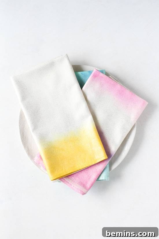 Culinary Creations: 16 Fabric DIY Projects for Home Chefs 16 Three folded tie-dye napkins, featuring white and yellow, pink and white, and blue and white designs, displayed on a white plate.