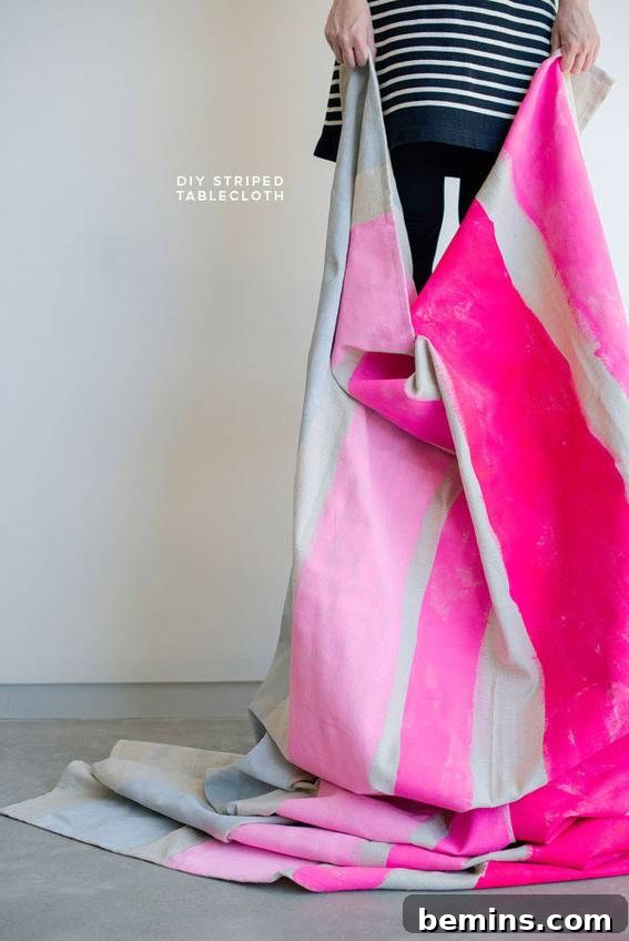 Culinary Creations: 16 Fabric DIY Projects for Home Chefs 6 A person holding up a pink and white striped tablecloth, showcasing its vibrant design.