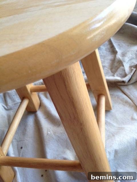 Double the Seating: A DIY Stool Split 14 Edge of a light-colored wood stool with a round seat. Showing the original shiny finish on the stool.