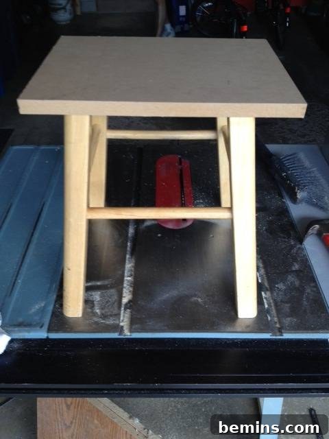Double the Seating: A DIY Stool Split 5 Square table of raw wood on top of a blue metal base, forming the new seat of the stool.