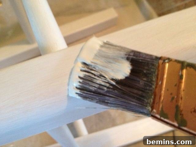 Double the Seating: A DIY Stool Split 6 Brush applying white paint to the stool legs. Close up of the painting process.