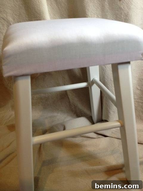 Double the Seating: A DIY Stool Split 8 White chair with a white seat, demonstrating the upholstered base layer.