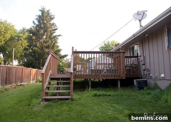 From Cluttered to Chic: A Backyard Deck Transformation 3 Overgrown grass around the stairs of the old, large deck in the backyard.