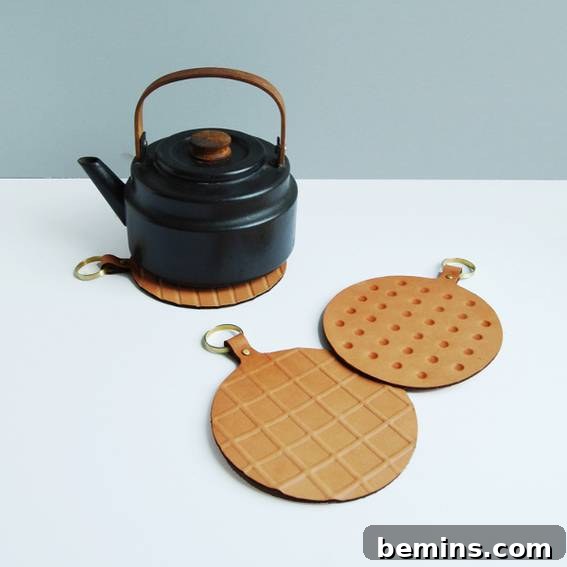 A black kettle next to two brown leather trivets.