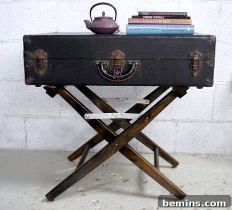 An antique suitcase transformed into a side table, topped with a copper teapot and a stack of sideways-leaning books.