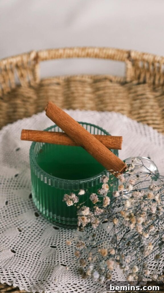 Aesthetic green drink with cinnamon sticks and flowers on lace in wicker basket.