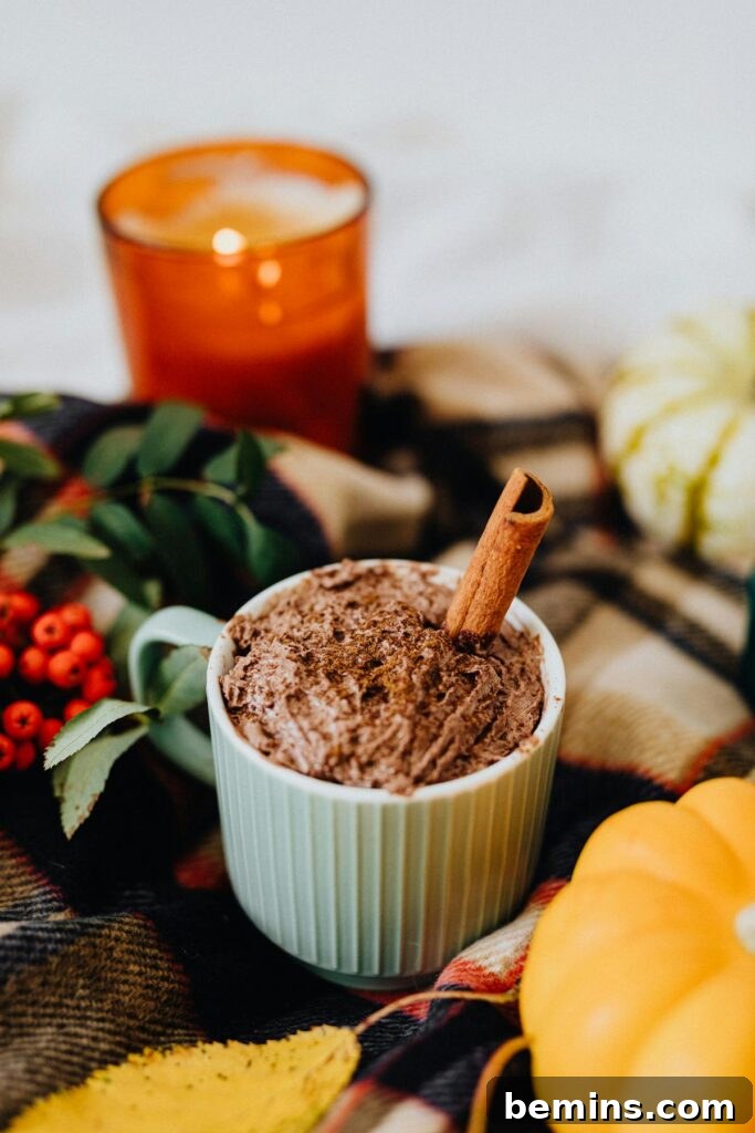 Warm autumn setup with hot chocolate and cinnamon in cozy decor.