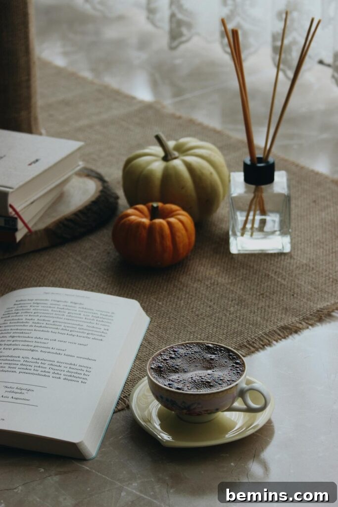 A warm autumn atmosphere with coffee, books, pumpkins, and diffuser sticks for a relaxing day at home.