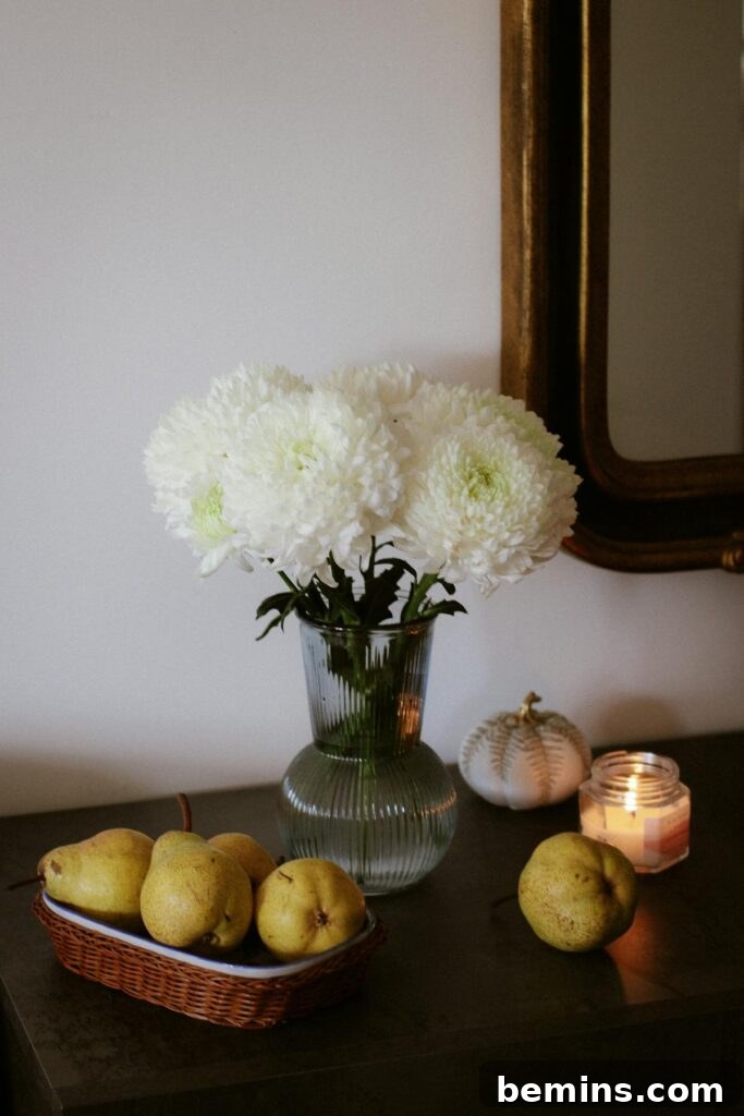 A serene still life featuring white flowers, pears, and a lit candle on a table.