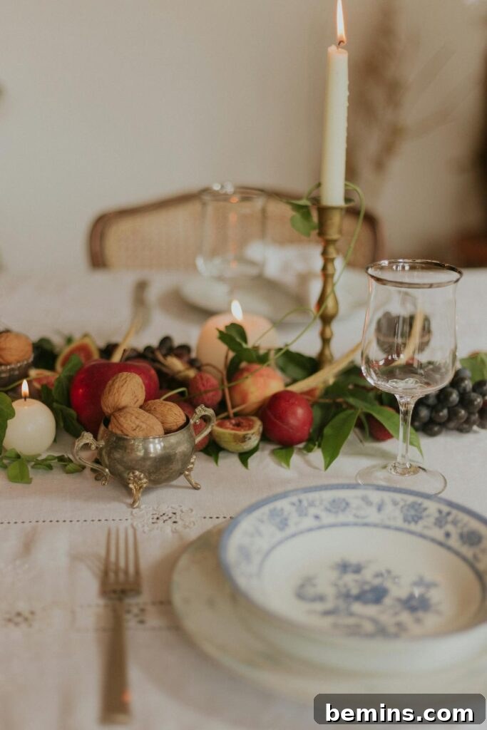 A beautifully arranged table setting with a candle, fruits, nuts, and elegant plates, perfect for special occasions.