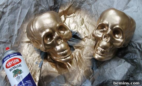Two metallic gold skull bookends next to a can of spray paint.