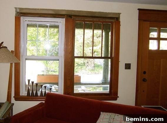Two windows are hung near a wall near a wooden door.