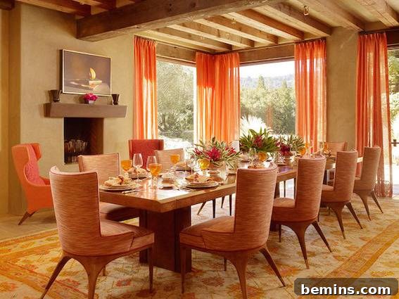 A dining table set for a meal, featuring rounded orange chairs, orange curtains, and a rug with orange accents.