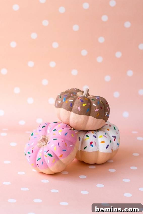Pumpkins painted in the form of popular doughnuts, sitting near a polka-dotted area. Delicious DIY donut pumpkins.