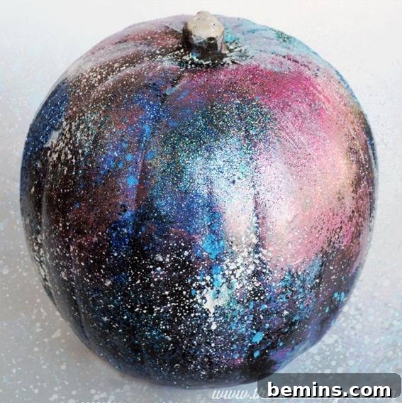 Pumpkin painted with colors and sparkles resembling a night sky. Mesmerizing DIY galaxy art pumpkin.