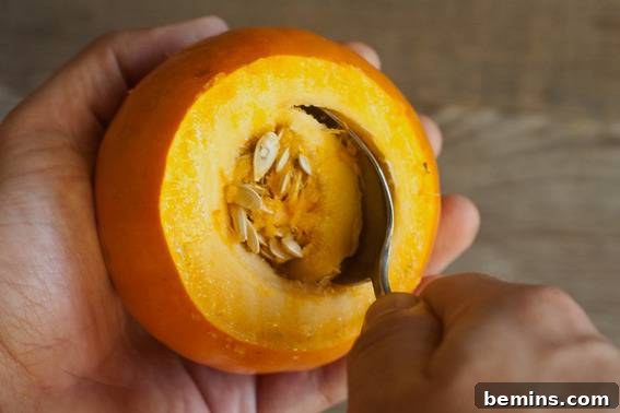 Scooping out the seeds and pulp from a pumpkin to prepare it for use as a cup.