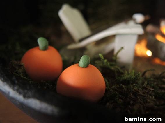 Two orange pumpkins with green stems made of clay sit on a black plate as a part of a centerpiece.
