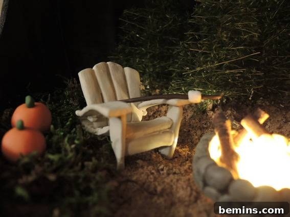 A small off-white chair sits near a campfire and has two pumpkins off to the side.