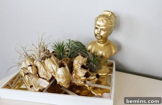 A close-up of a decorative tray displaying a gold bust of a smiling lady, surrounded by greenery and other elegant gold accents.