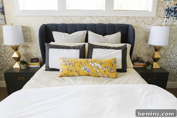 A beautifully arranged bed with white linens, accented by black, white, and yellow pillows, flanked by elegant gold lamps.