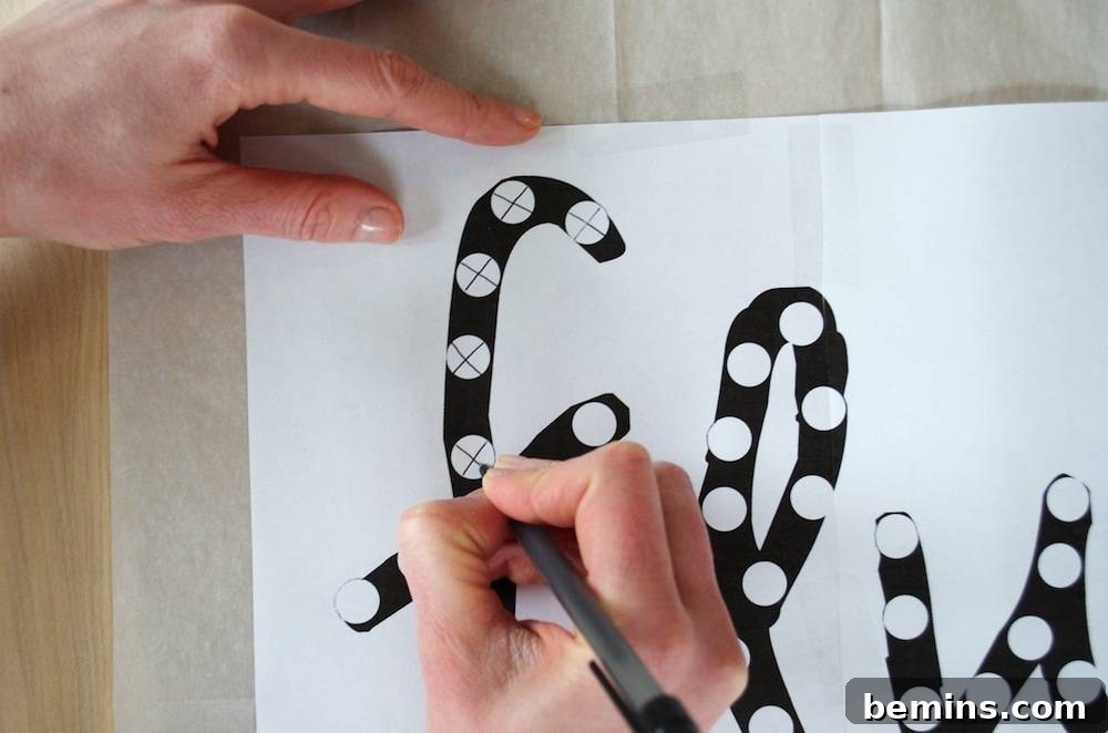 How to Design Your Own Dazzling Light-Up Sign 5 Close-up of the word design on the plywood, with each light placement marked with an 'X' to guide the drilling process.