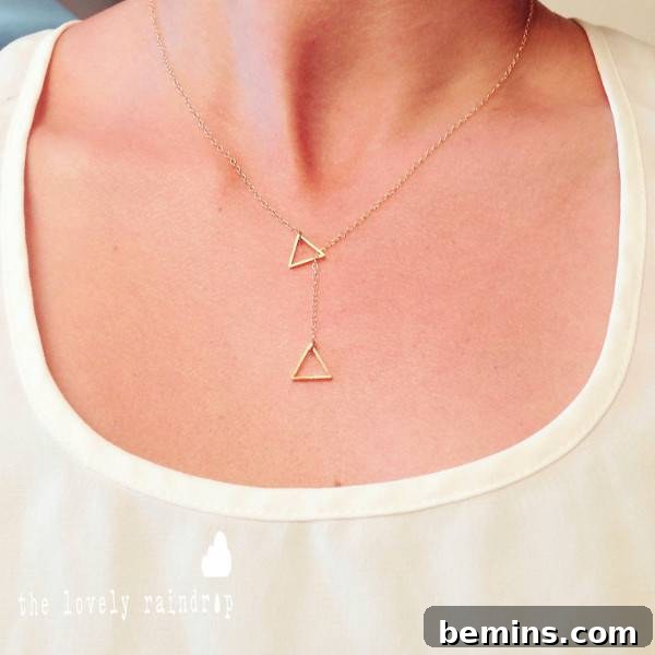 A person is wearing a chain with triangles on it. Tiny triangle lariat necklace from The Lovely Raindrop.