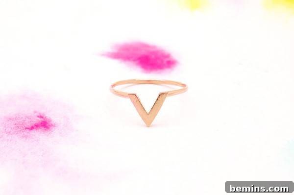 A pink blob is seen over a v shaped golden ring. Brushed rose gold chevron ring from Recoco NYC.