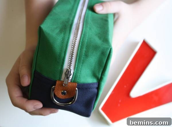 A person is showing green color zip bag. Boxy Box Travel Pouch from Christina’s.