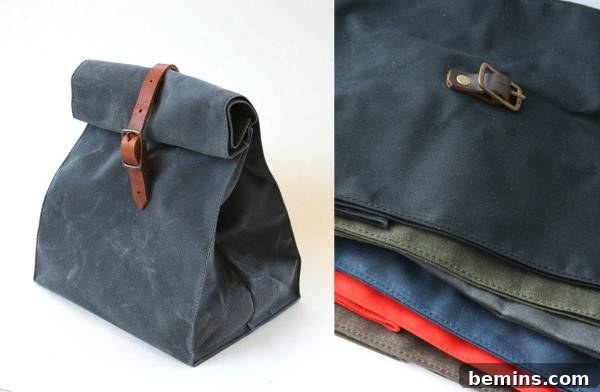 A dar blue bag with a leather strap next to several different colored bags laying flat. Waxed Canvas Lunch Bag by Overlap.