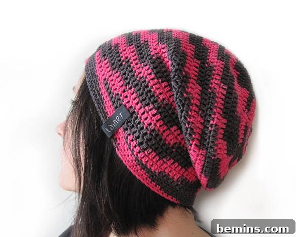 A woman with dark hair is wearing a pink and grey beanie. Crochet slouchy beanie from LainDesign.