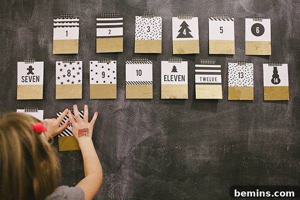 A girl puts up gold white and black pages on a wall to create an advent calendar.