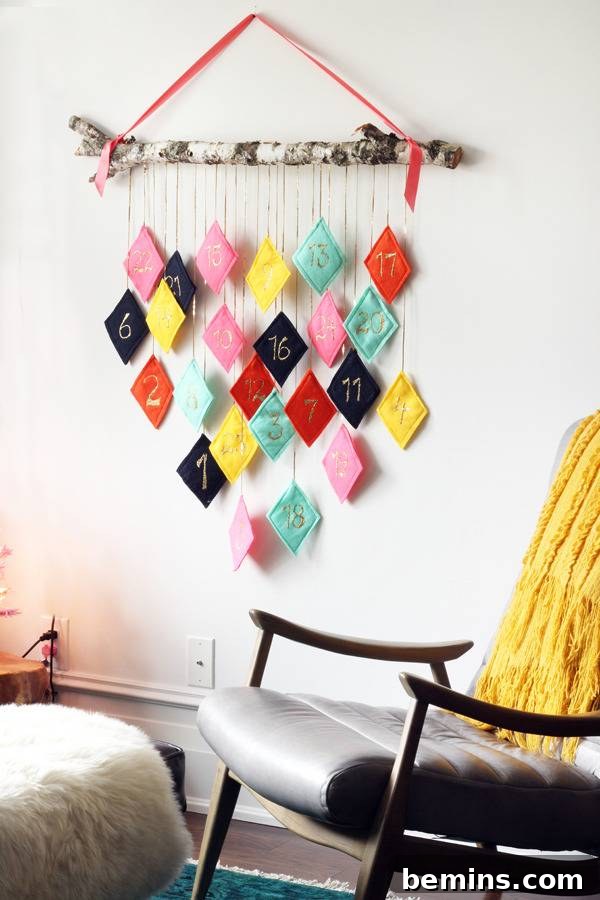 Multicolored diamond shapes hanging from a branch which is held up by an orange strap.