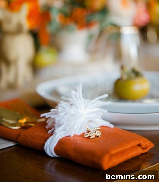 Quick & Easy Thanksgiving Table: 13 DIY Ideas Under an Hour 11 Charmed yarn pouf napkin ring with a brown napkin wrapped with a white band.