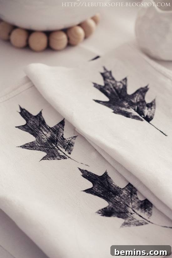 Quick & Easy Thanksgiving Table: 13 DIY Ideas Under an Hour 5 Stamped leaf napkins with silver leaves on a white surface.