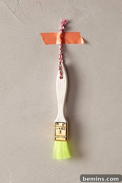 The Ultimate Ornament Roundup: 12 Must-Have Decorations for Your Tree 5 A small lime green paint brush ornament.