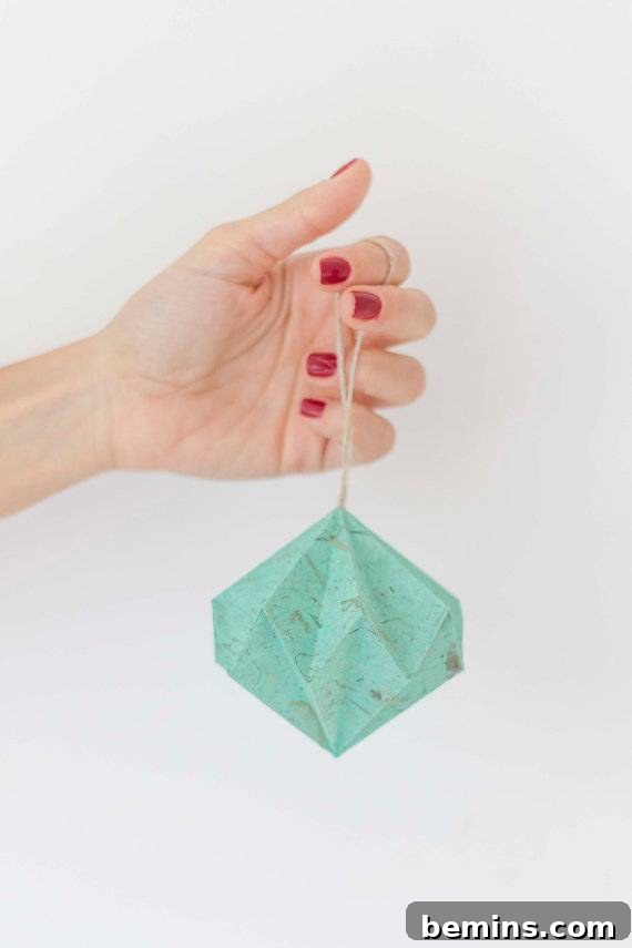 The Ultimate Ornament Roundup: 12 Must-Have Decorations for Your Tree 7 Hand holding a small, blue paper lantern ornament.