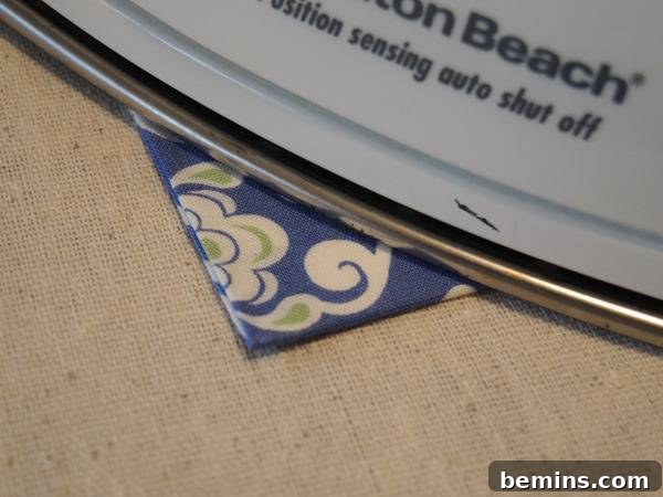 A blue floral card is sitting under a white computer, indicating the ironing stage for a smooth finish.