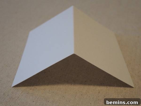 White paper folded in half and turned back, demonstrating the folding technique for the poster board template.