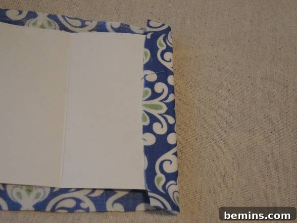 Blue and white fabric with a white sheet on it sitting on top of a carpet, showing the folded and glued fabric edge.
