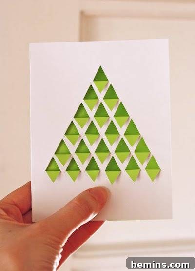 A person holds up a card with a green triangular Christmas tree.