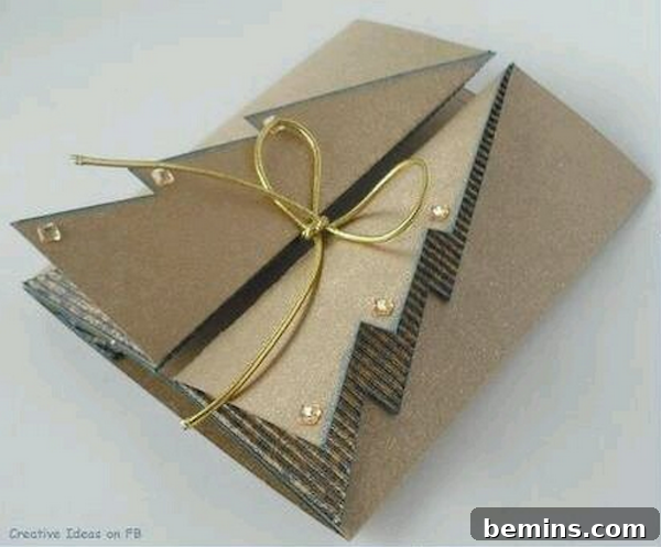 A craft paper card folded to resemble a Christmas tree is tied with thin gold ribbon.
