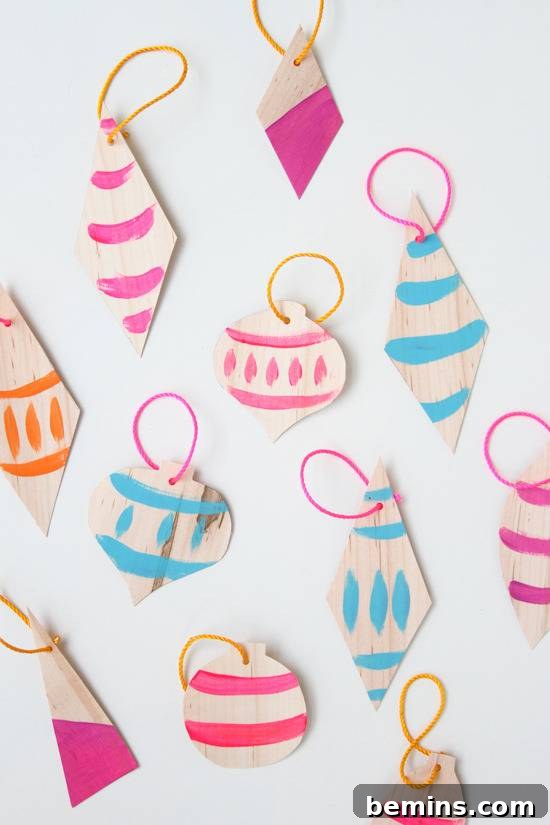 A collection of colorful, artistically painted veneer ornaments, some hanging, some laid flat, displaying their unique designs.