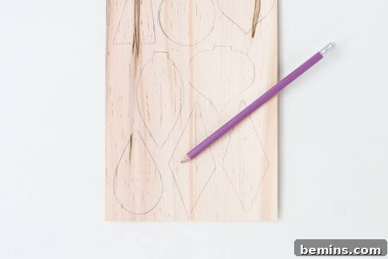 A thin sheet of natural wood veneer marked with various hand-drawn ornament shapes, ready for cutting.