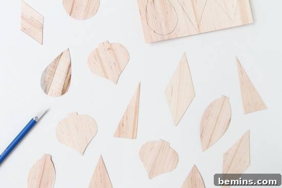Various shapes meticulously cut from wood veneer using an X-Acto knife, demonstrating precise crafting.