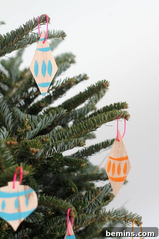 Close-up of a beautifully painted veneer ornament hanging among the green needles of a Christmas tree.